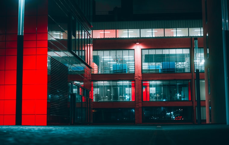 A commercial building at night, lit red, with controlled entrances